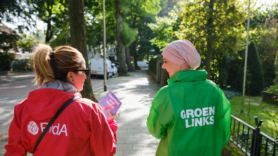 Foto van twee mensen met PvdA en GroenLinks jasjes aan, met aan de rechterkant Esmah Lahlah.