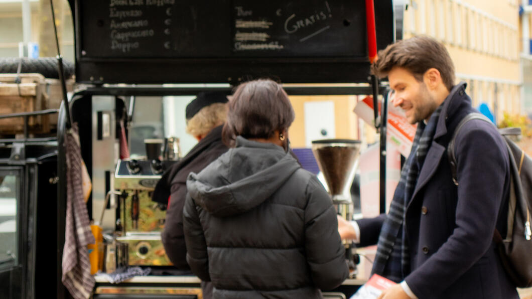 Koffiekar met twee mensen in gesprek over de campagneflyer