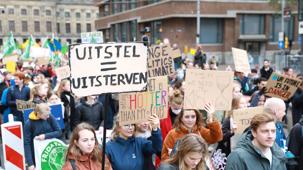 Tijdens de klimaatmars loopt een grote groep mensen met borden met klimaatleuzen