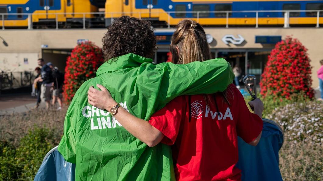 twee personen met een groene en rode jas omhelzen elkaar