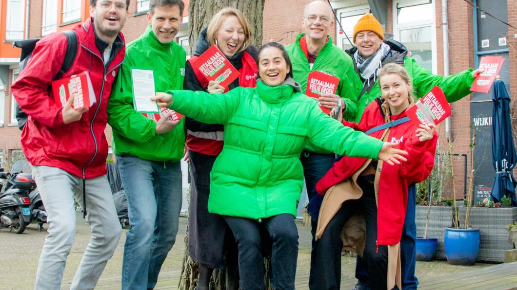 een groep mensen in groene en rode jassen poseren met flyers