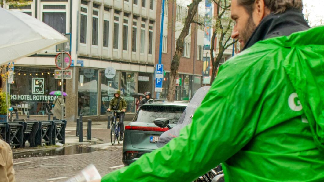 persoon met groene jas staat buiten te flyeren