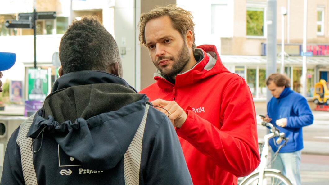 persoon in rode jas staat te flyeren en is in gesprek