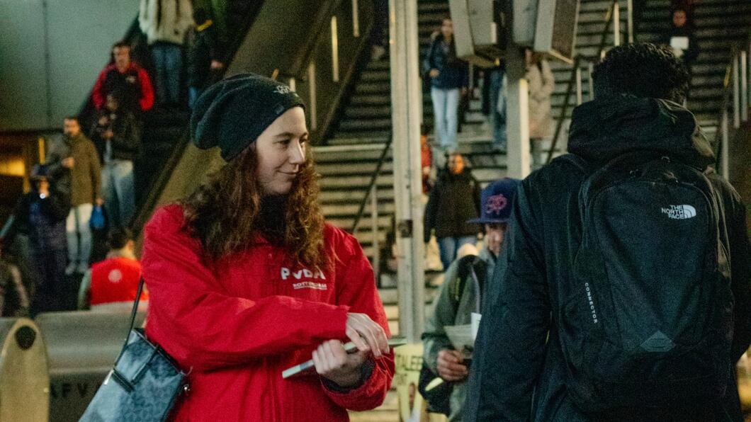 persoon in rode jas staat te flyeren