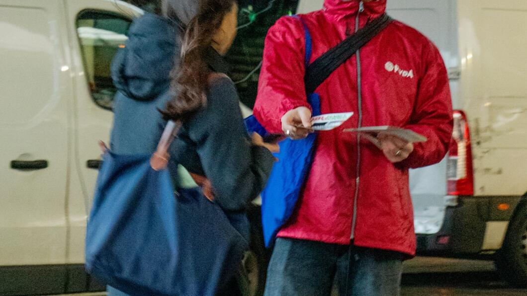 persoon in rode jas staat te flyeren