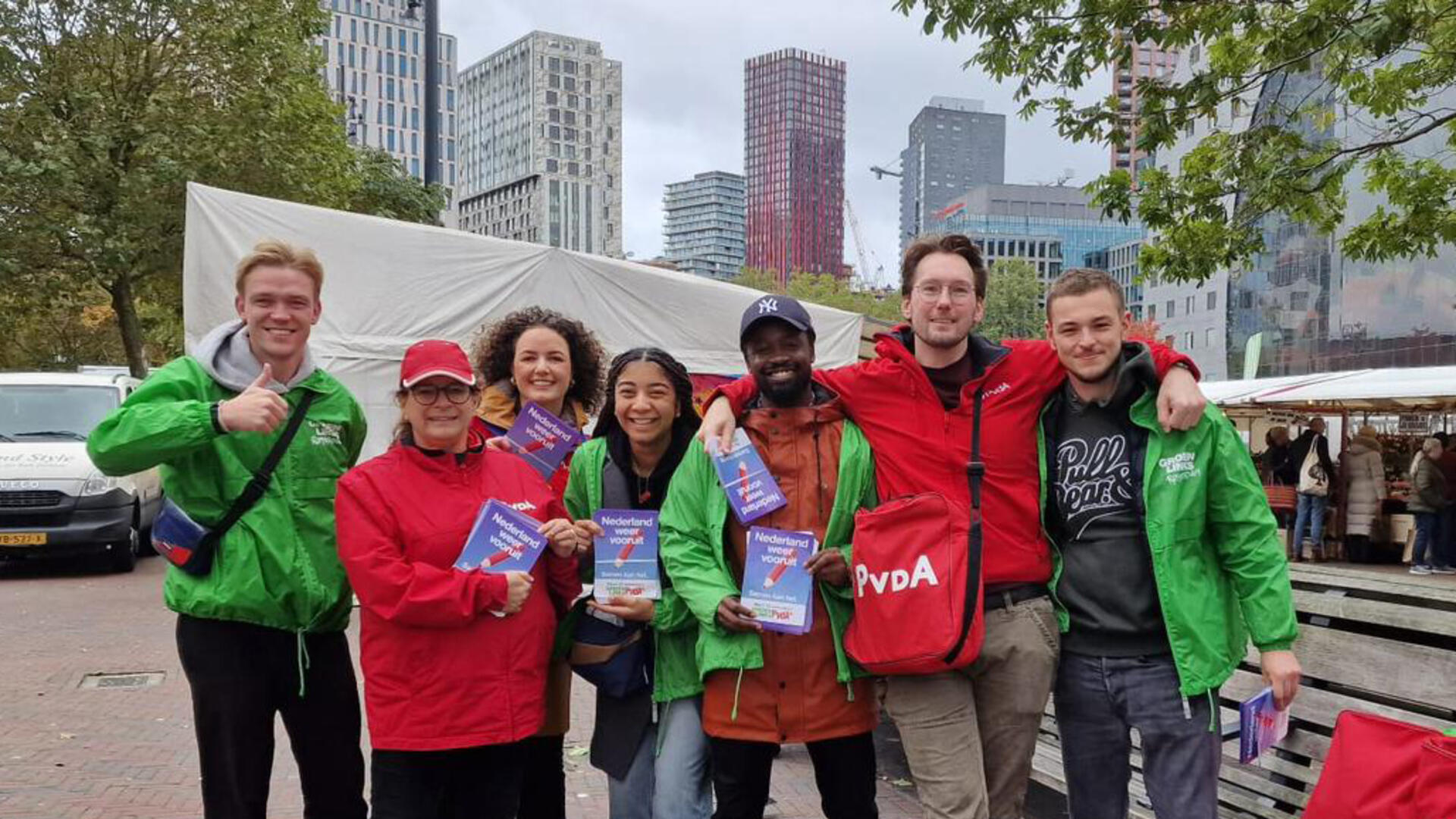 Vrijwilligers op de markt van Blaak met groene en rode jasjes aan en flyers in hun handen