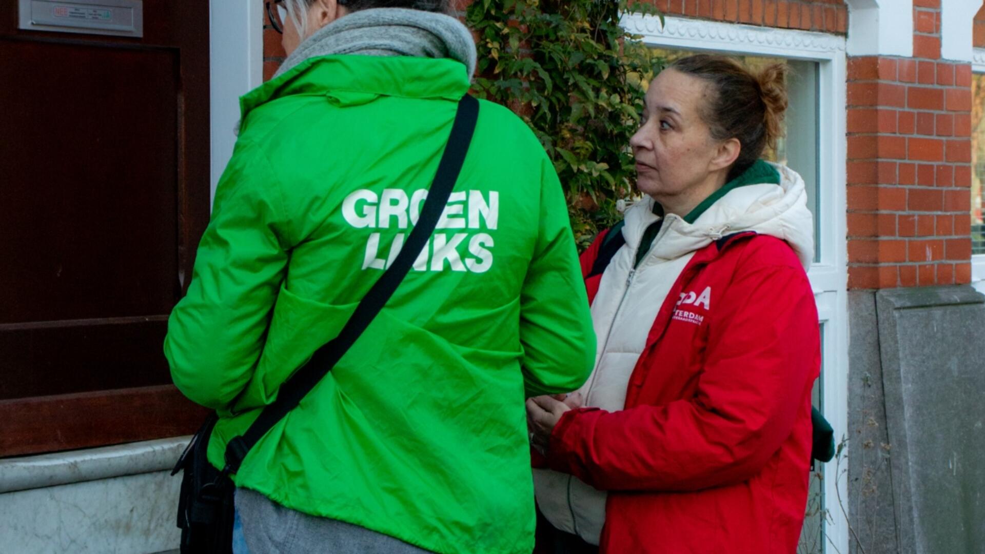 Twee mensen in groene en rode jas die huis-aan-huis aan het flyeren zijn
