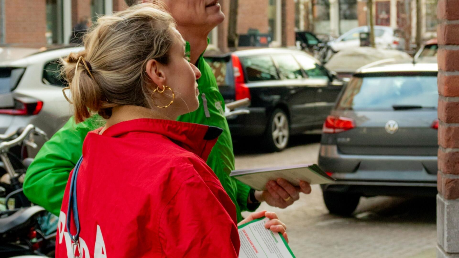 twee mensen met rode en groene jas staan te flyeren