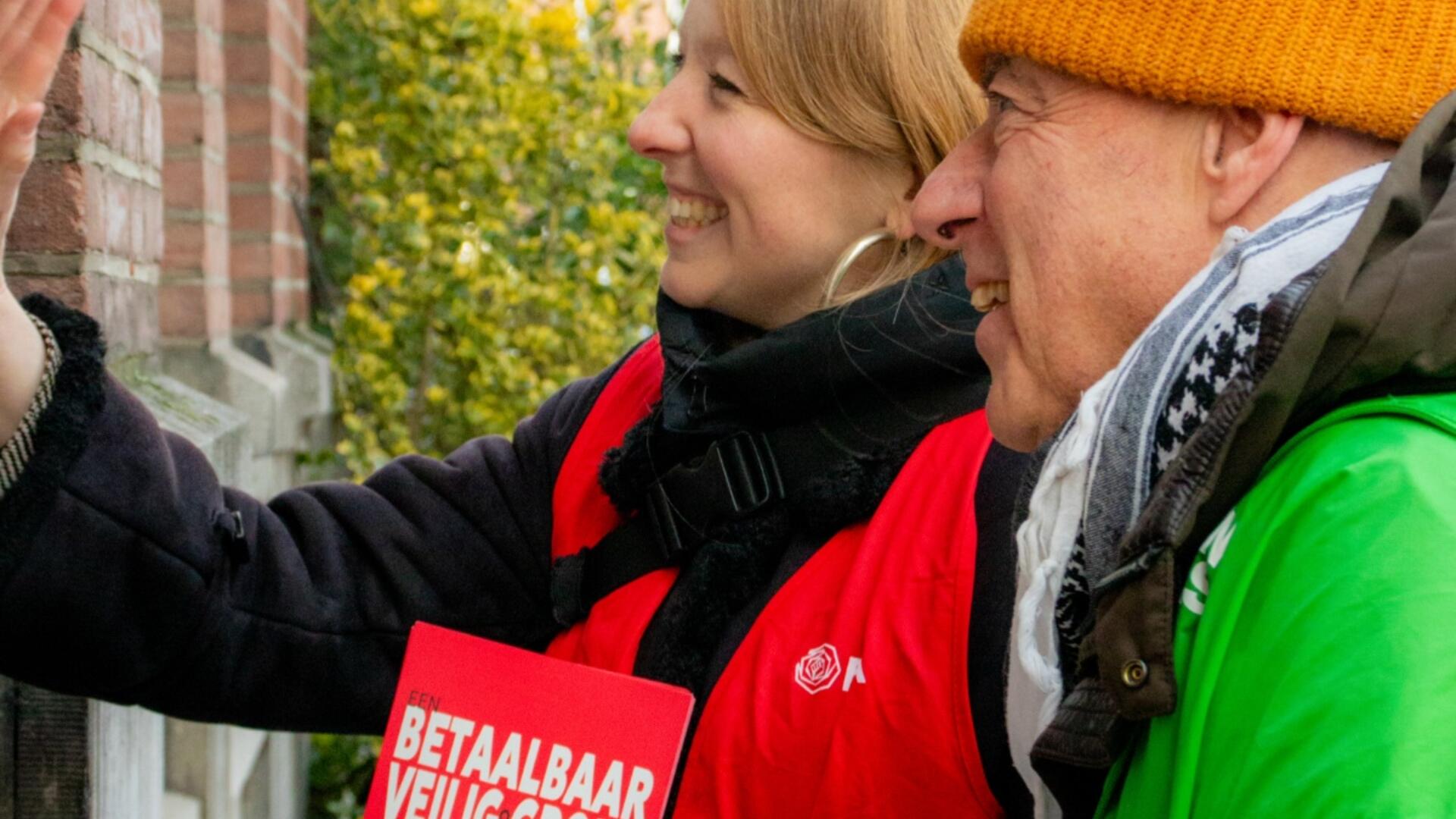 twee personen met rode en groene jas staan te flyeren