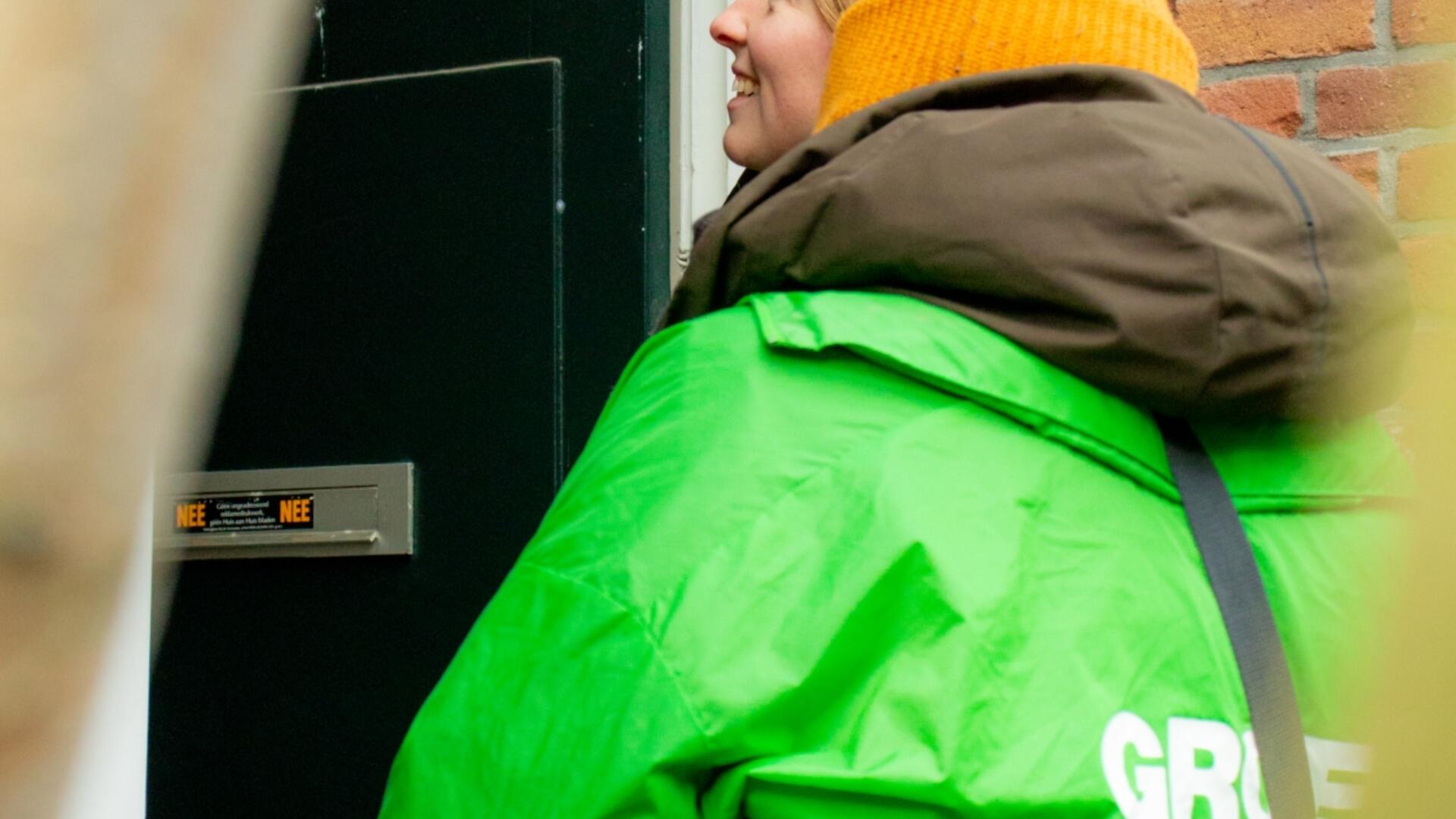 twee mensen met groene en rode jas die staan te flyeren en lachend in gesprek zijn