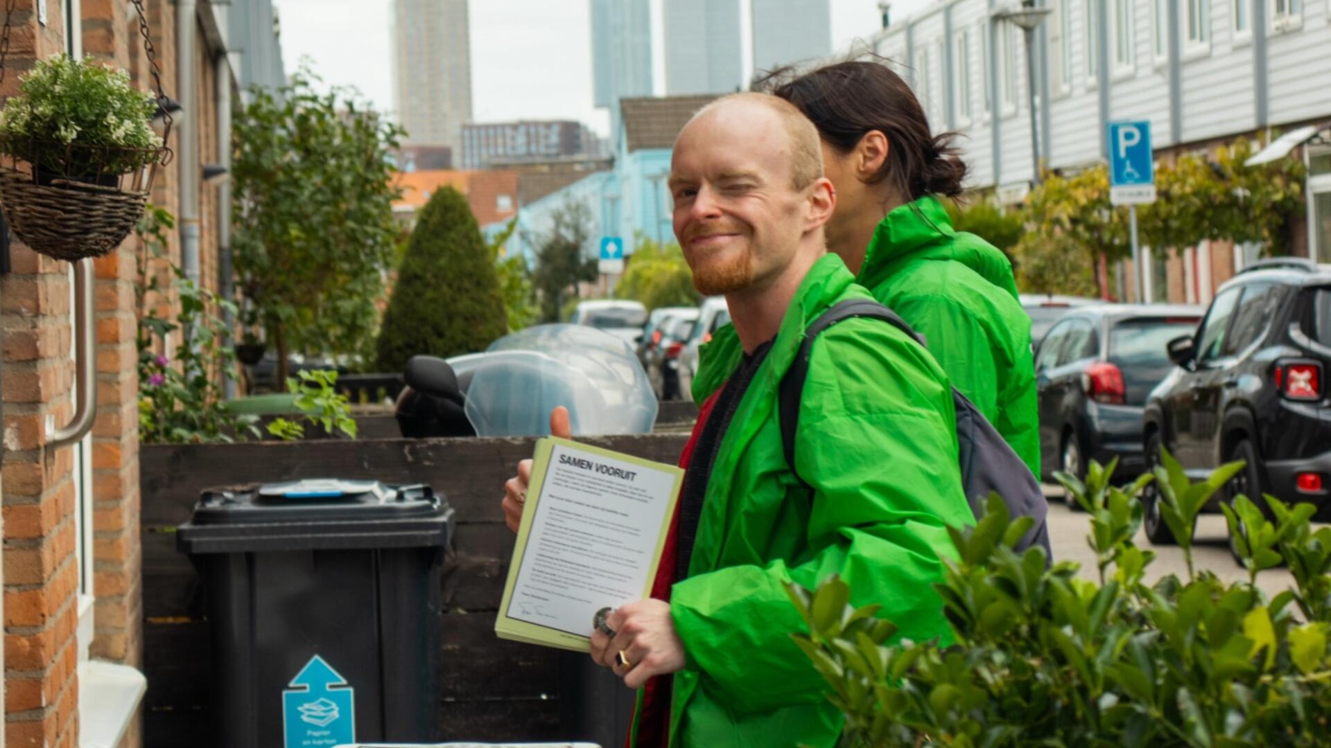 twee mensen met groene jassen staan te flyeren