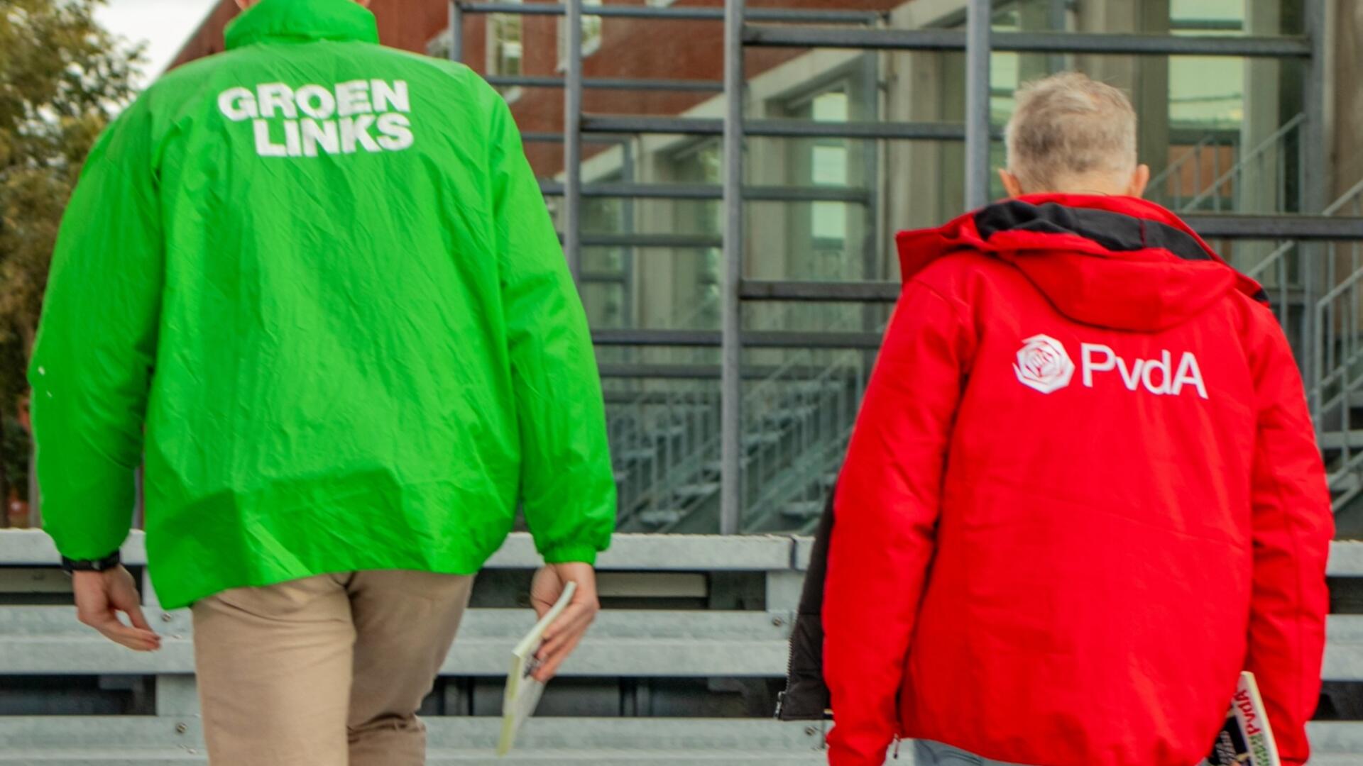 twee mensen met rode en groene jas lopen buiten met flyers
