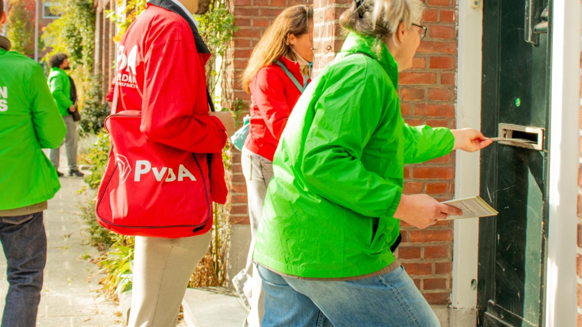 een groep mensen in rode en groene jassen staan te flyeren