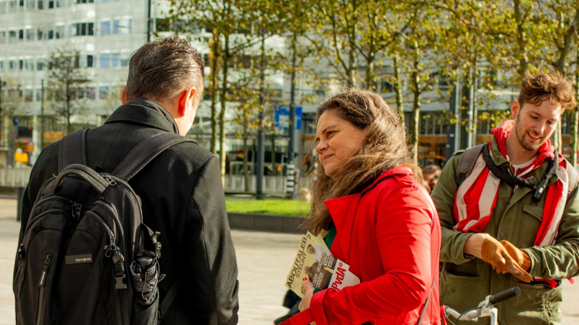 persoon met rode jas staat te flyeren