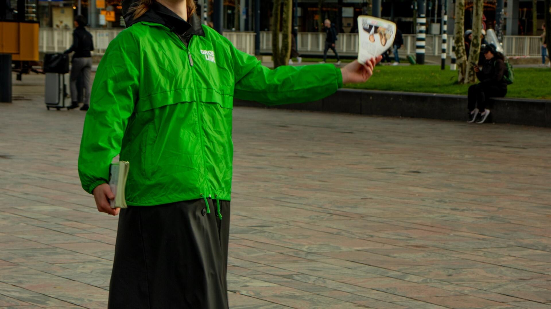 persoon in groene jas staat te flyeren