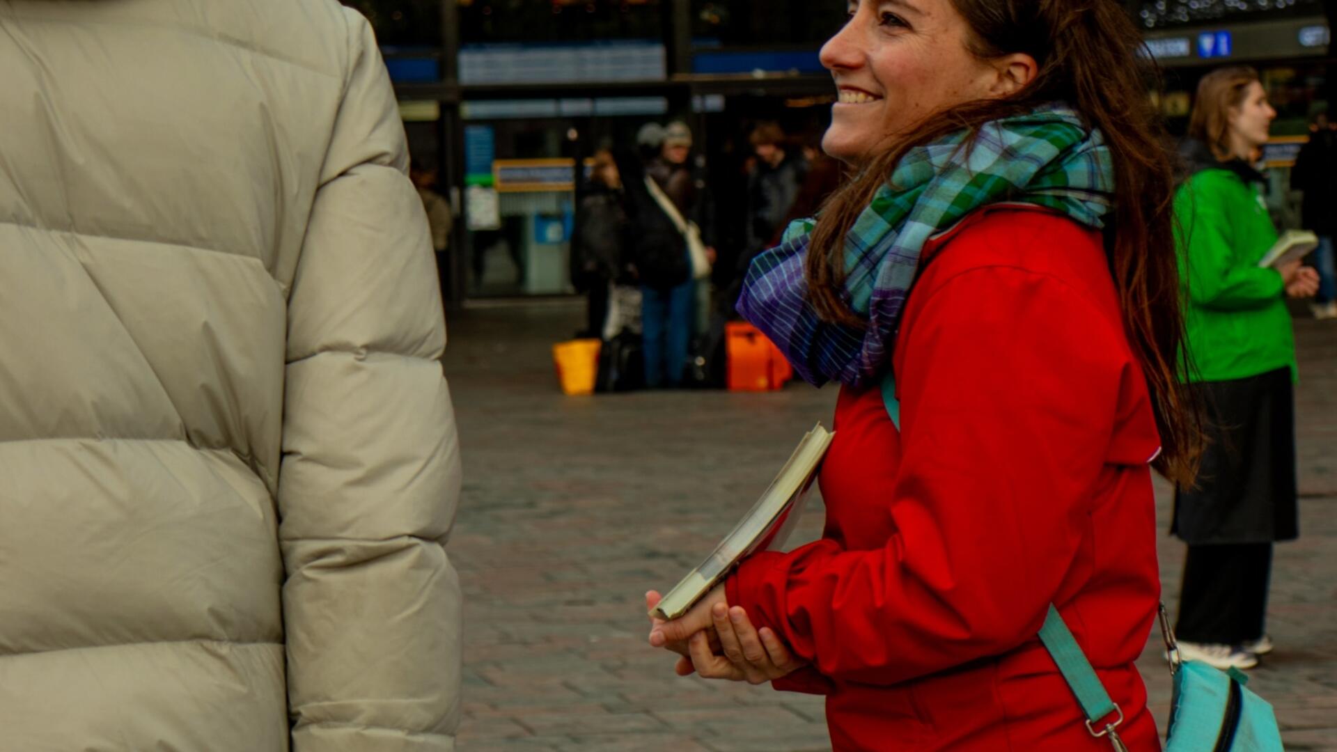 persoon in rode jas staat te flyeren bij het station