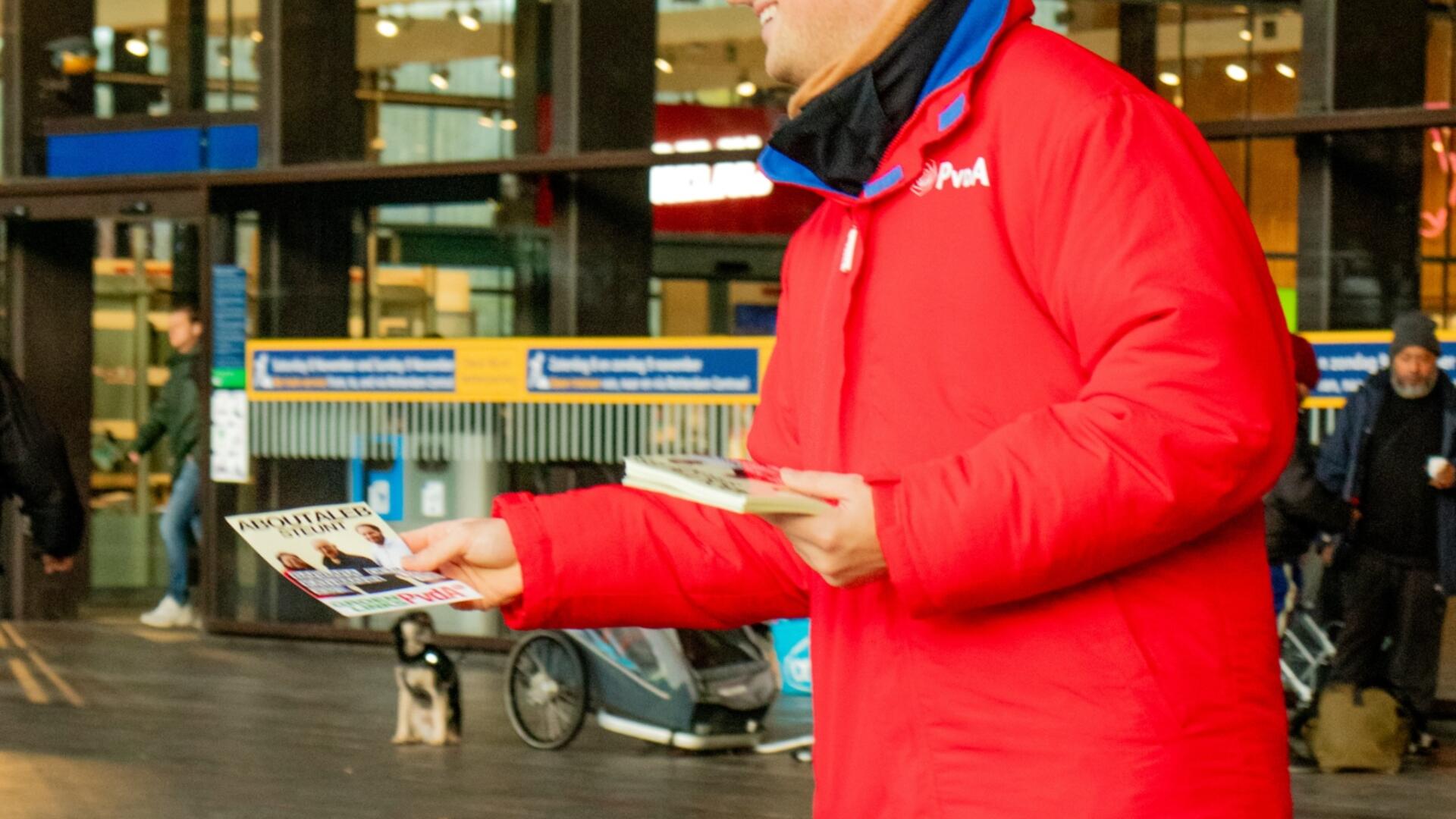persoon in rode jas staat te flyeren op het station