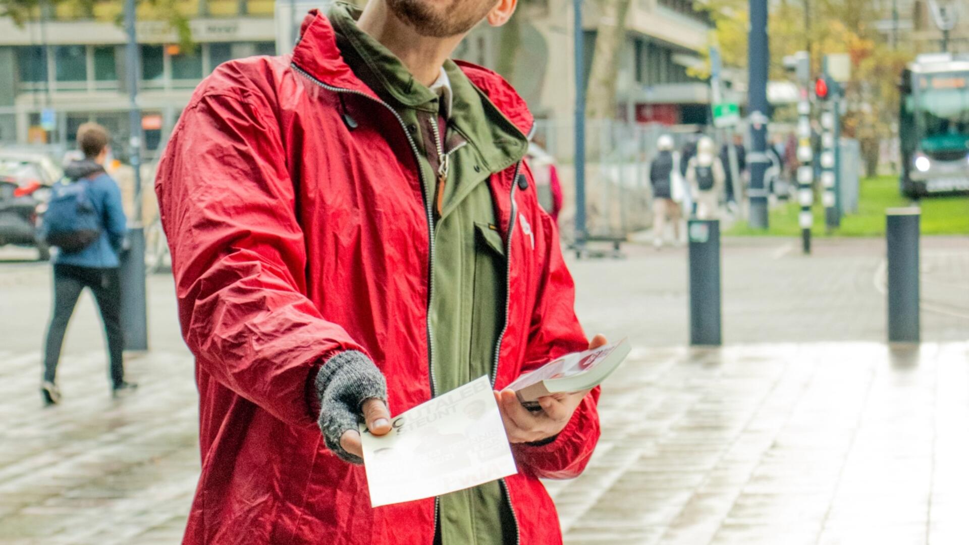 persoon in rode jas staat buiten te flyeren