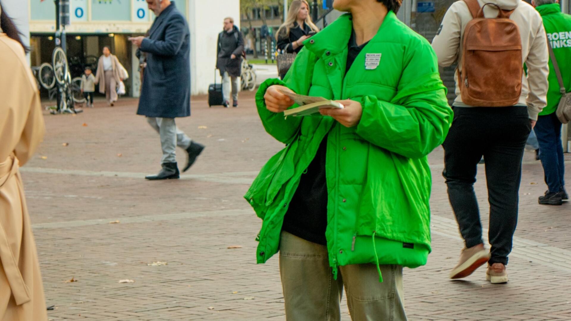 persoon in groene jas staat buiten te flyeren